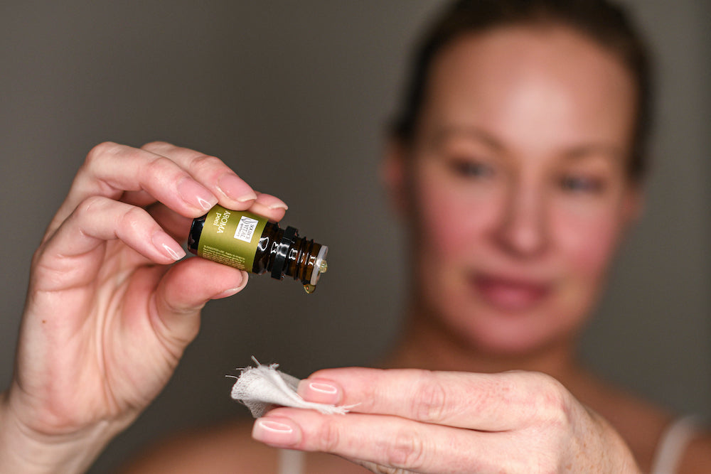 Woman holding bottle of Source Vital's Aroma Peel in one hand, and gauze in the other