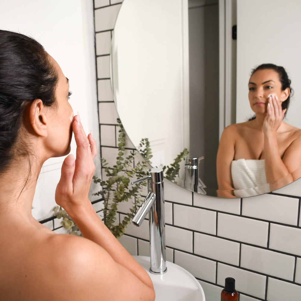 Woman touching face while looking in the mirror
