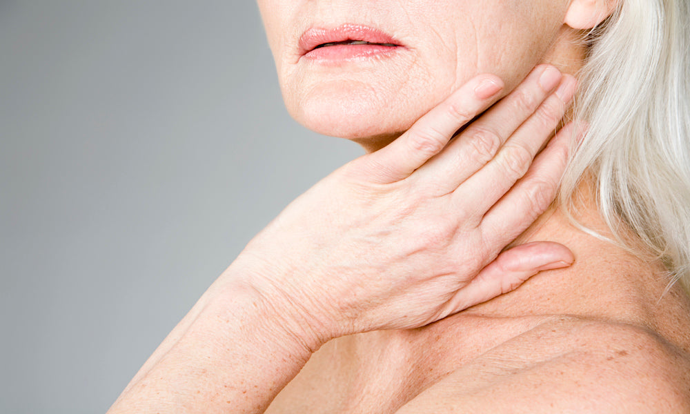 Older woman with grey hair with hand on neck