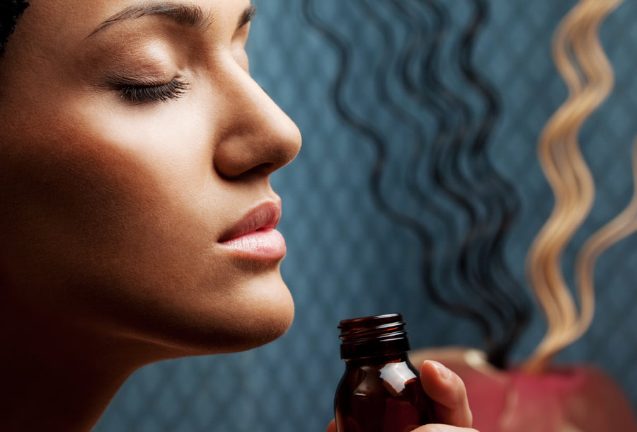Woman inhaling essential oil from amber bottle