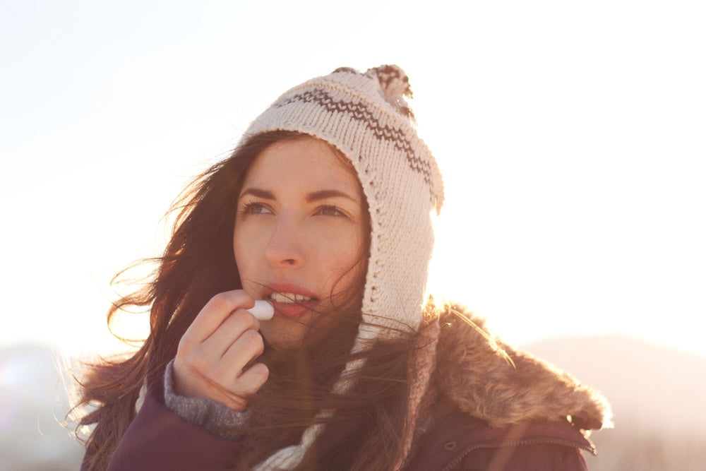 Woman bundled up in the cold applying chapstick