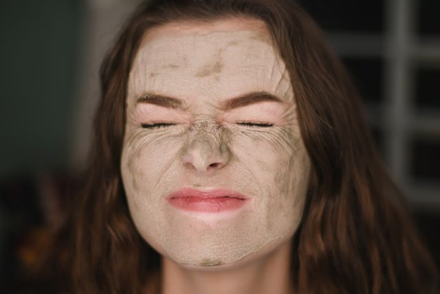 Brunette woman with green face mask on scrunching her face