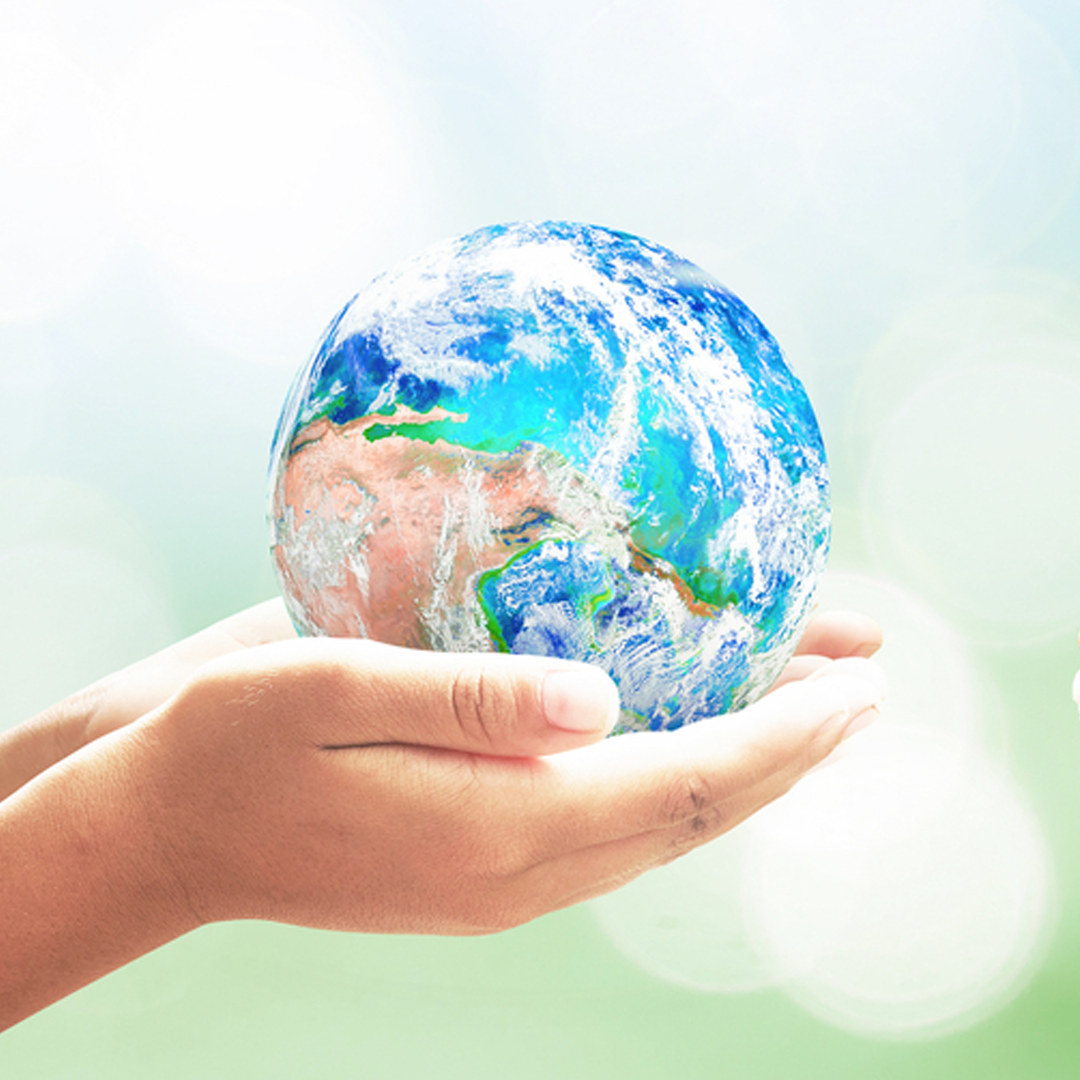 Hands Holding Earth against Green background