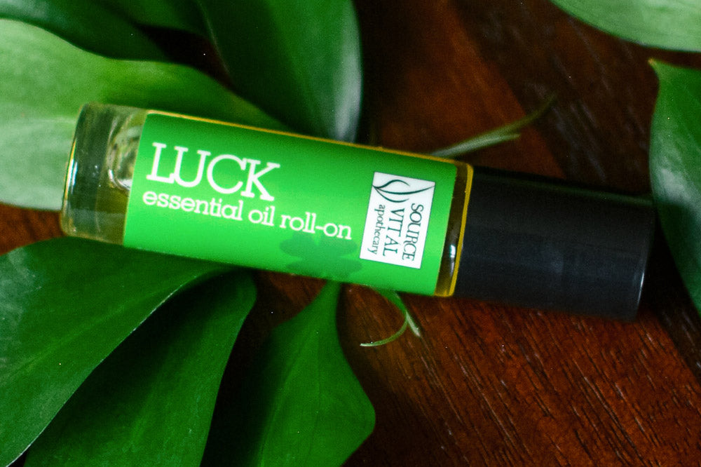 Luck Essential Oil Roll on On top of Greenery and Wood Top