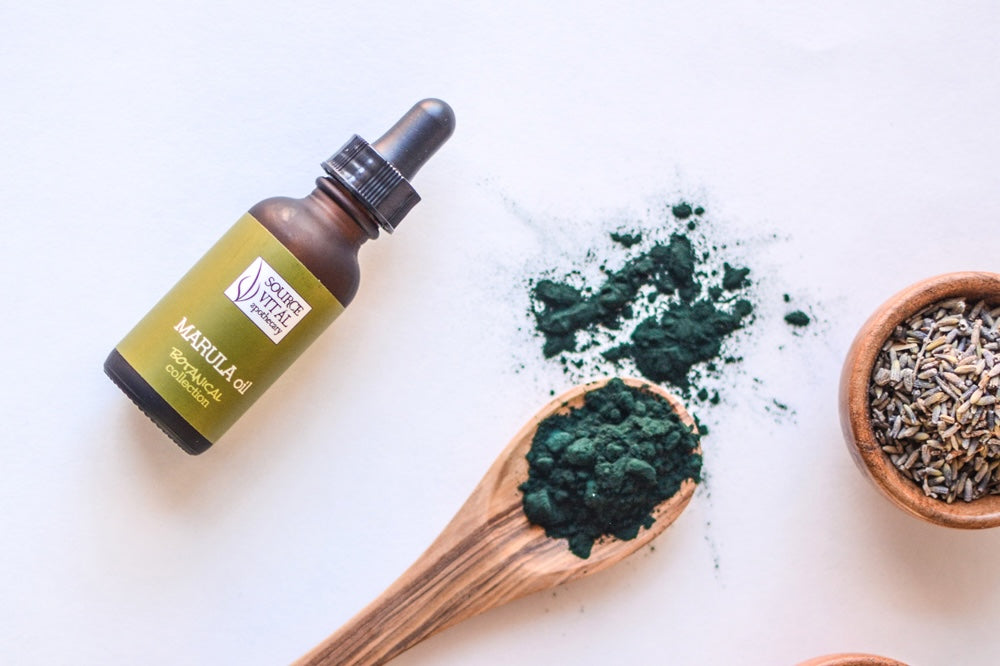 Marula Oil Botanical Bottle next to wooden spoon and bowl with natural ingredients