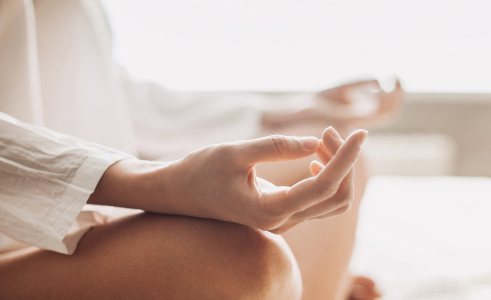 Woman in meditative position wearing white shirt