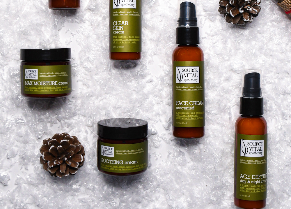 Assorted Source Vital Apothecary Moisturizers arranged in the snow along with pinecones