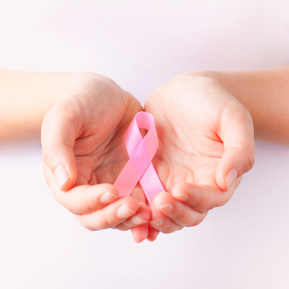 woman holding pink ribbon in the palm of her hands
