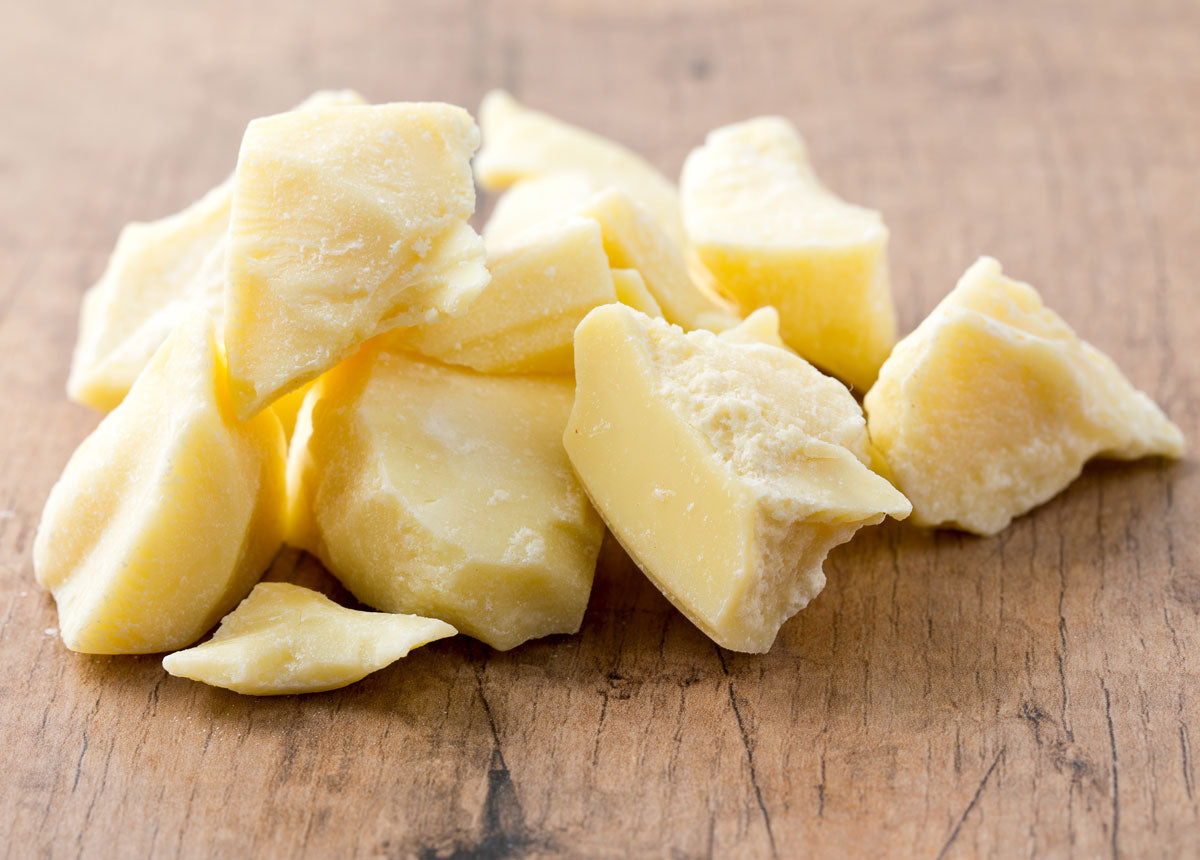 Chunks of raw cocoa butter in a pile on wooden table