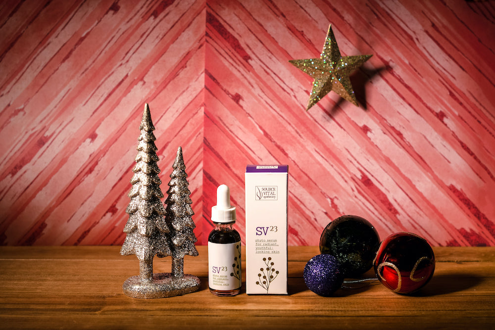 SV23 Phyto Serum with holiday baubles and silver trees. Against red background with star ornament