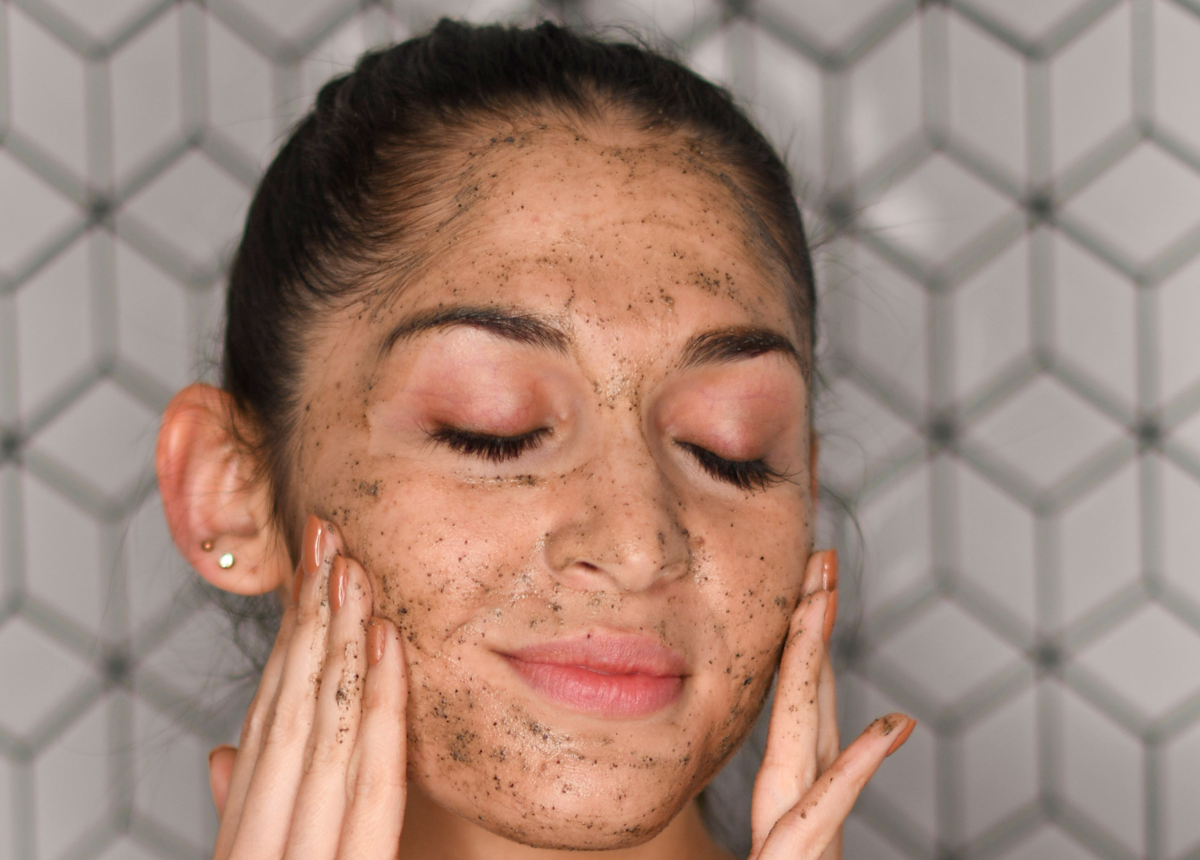 Woman with eyes closed rubbing exfoliator on her skin in circular motions