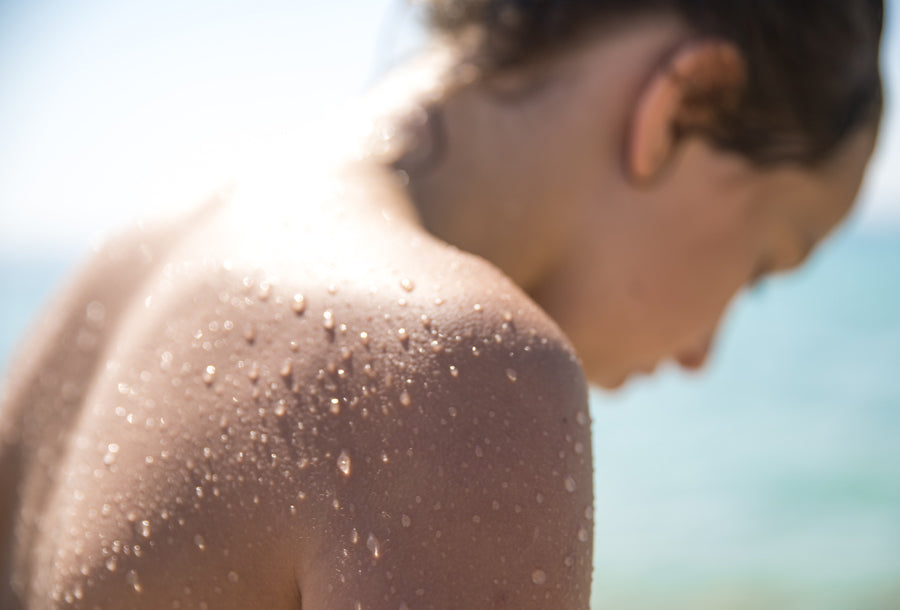 Woman standing in the sun with water droplets on back and shoulders