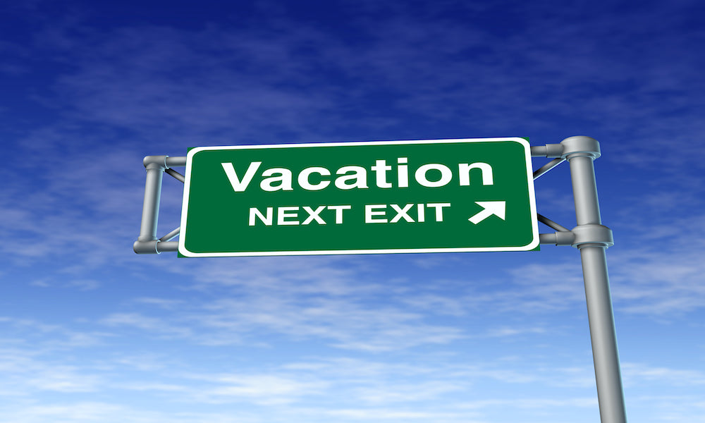 Exit Sign indicating "vacation next exit" against blue sky