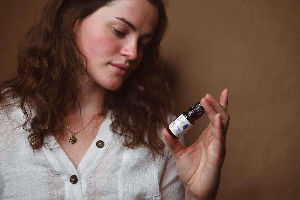 Woman looking at bottle of Source Vital Tea tree Essential Oil