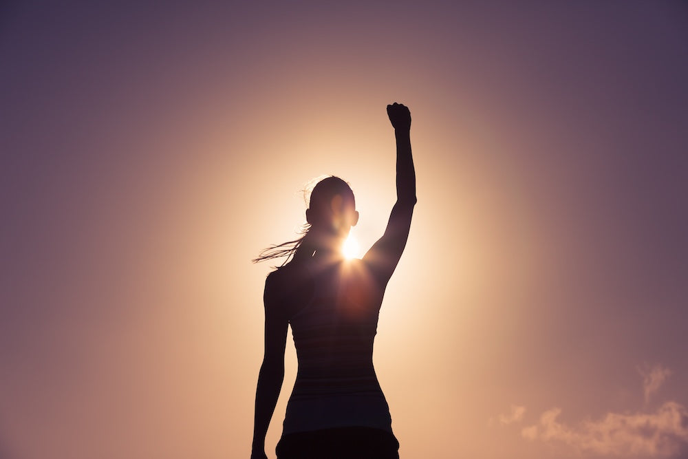 Shadow of woman cheering during sunrise