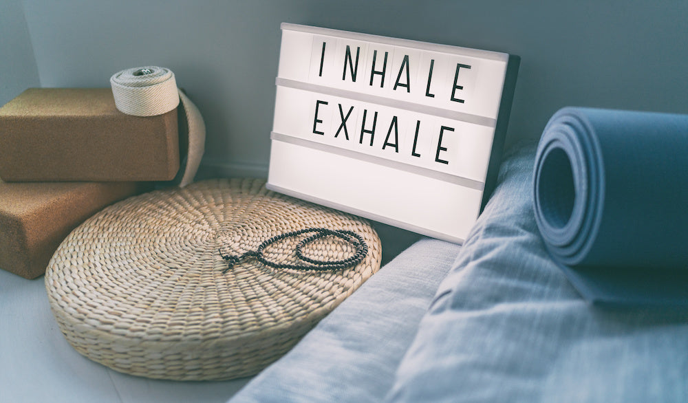 Lighted sign box that says "inhale, exhale" against various yoga props