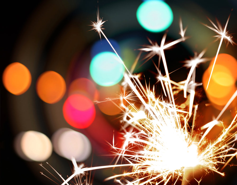Sparkler in front of colorful lights and black background