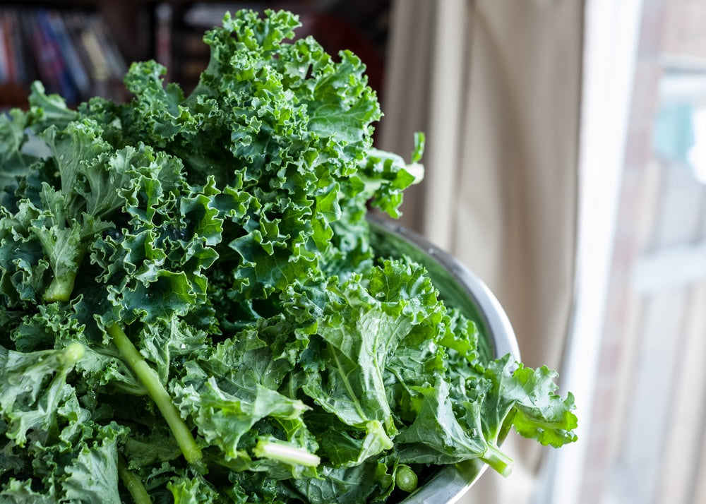 Bowl of leafy, green kale next to windowsill