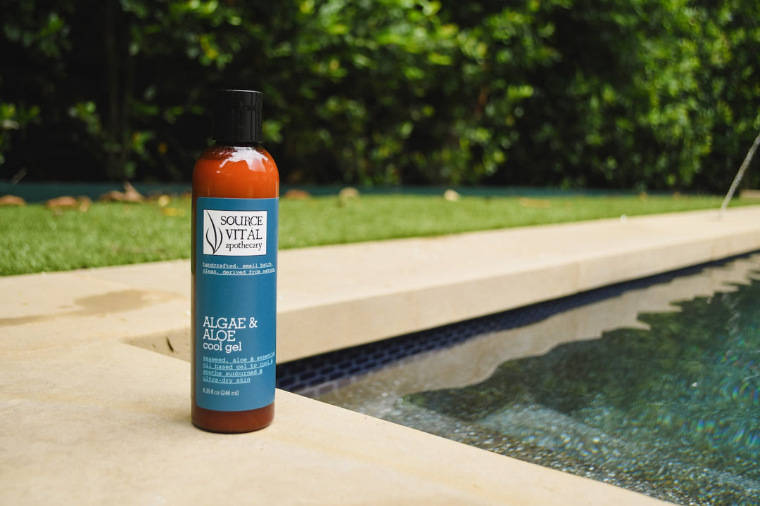 Bottle of Algae & Aloe Cool Gel sitting beside the pool with greenery in background