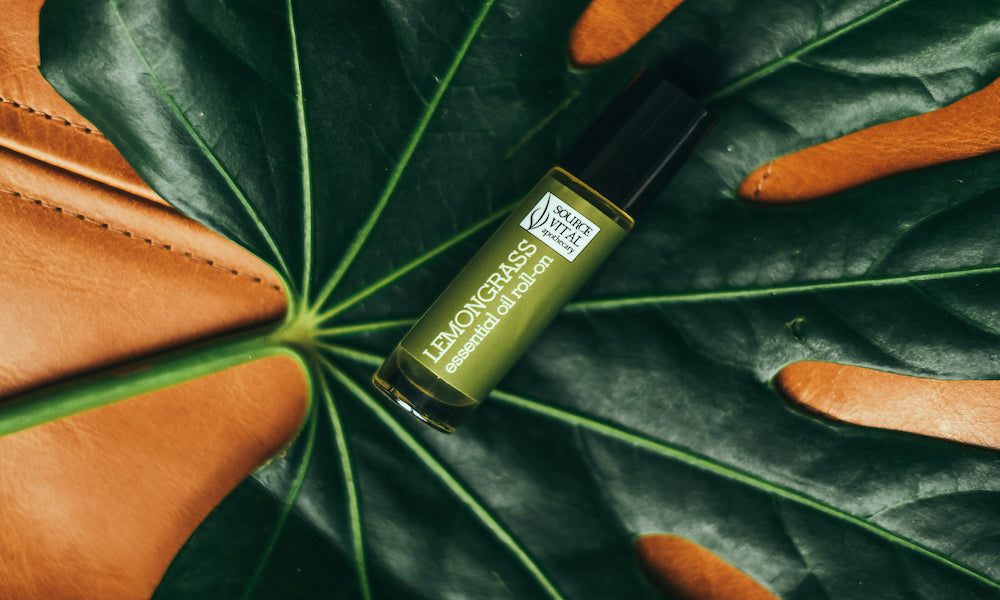 Lemongrass Essential Oil Rollerball on top of green leaf on orange leather background