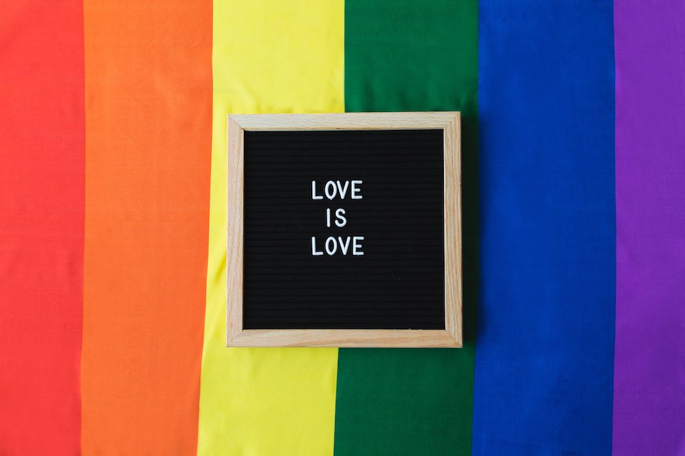Blackboard with text "love is love" on rainbow background for pride month