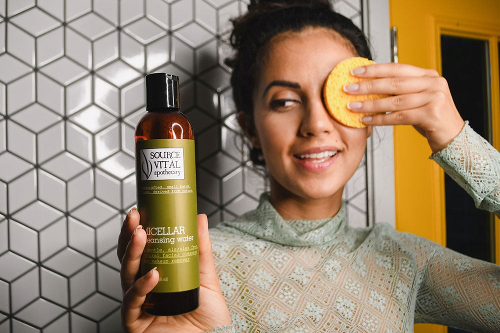 Woman cleansing her skin with Source Vital Micellar Water and sponge