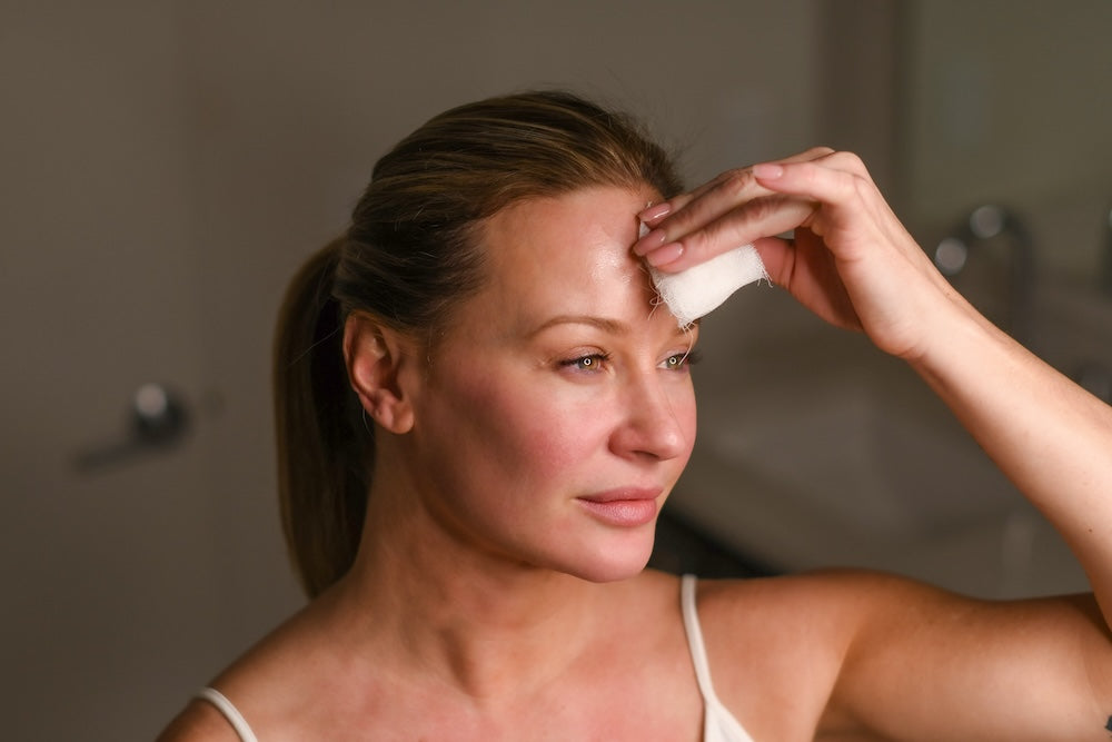Woman using Aroma Peel with gauze on glowing skin.