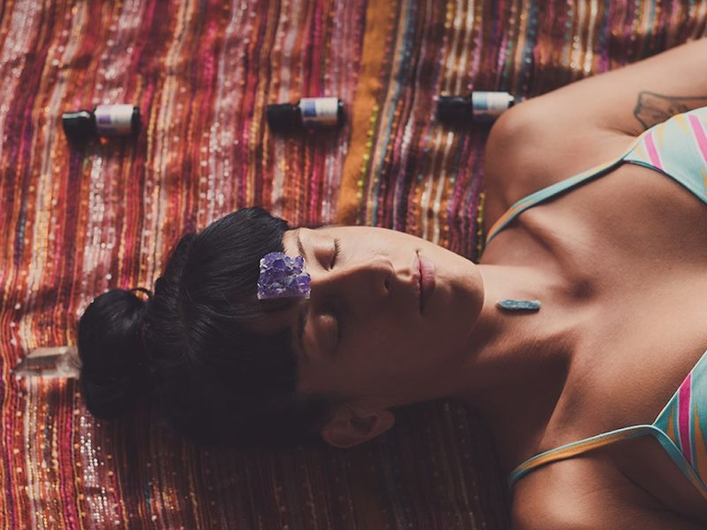 Woman meditating with crystals and oils surrounding her