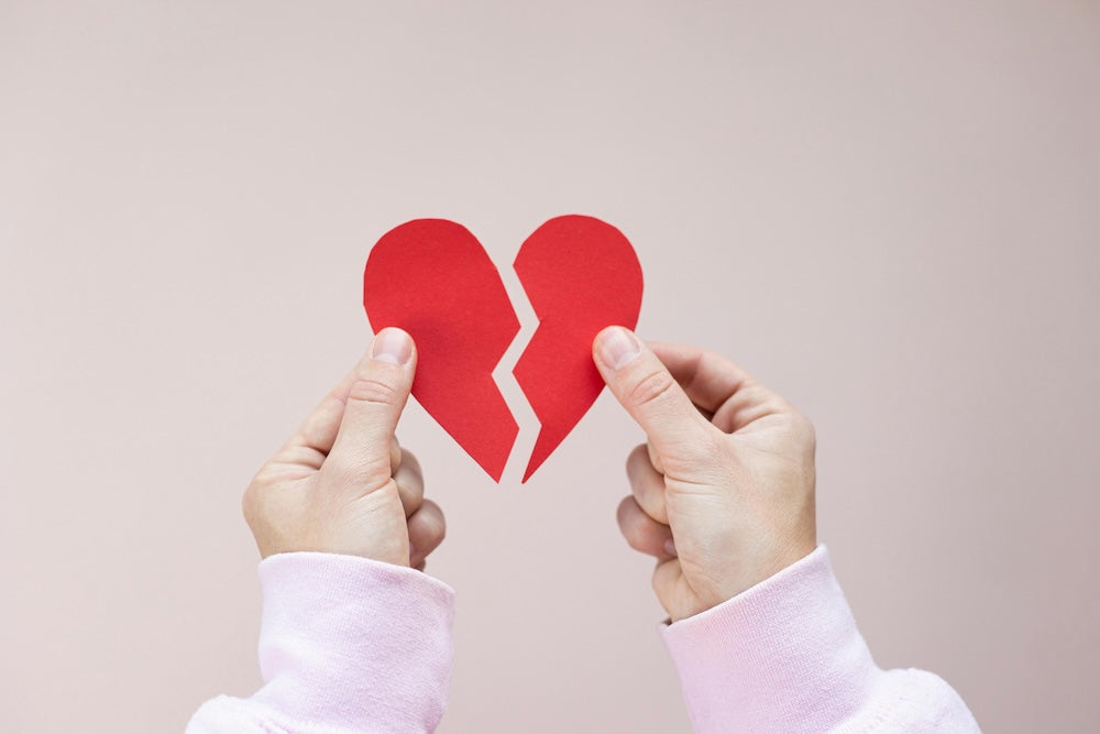 Woman holding red paper broken heart