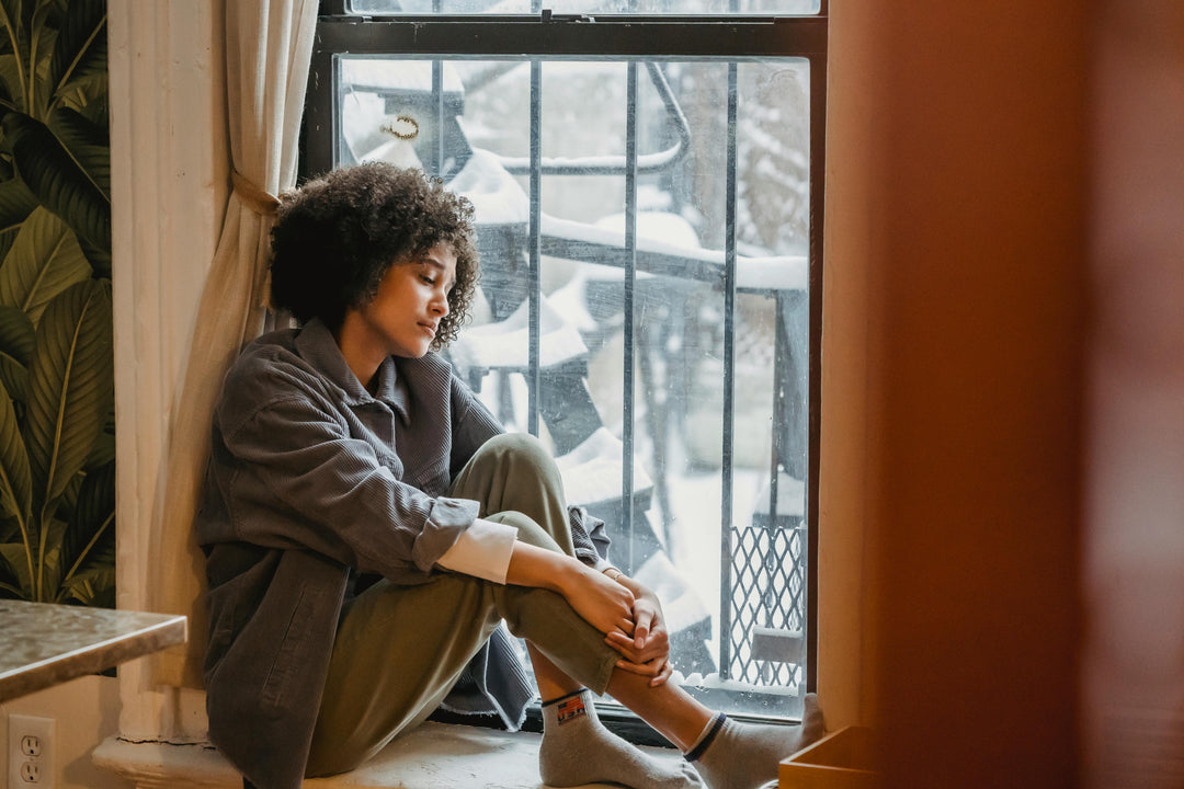 Woman sitting by window with snow outside