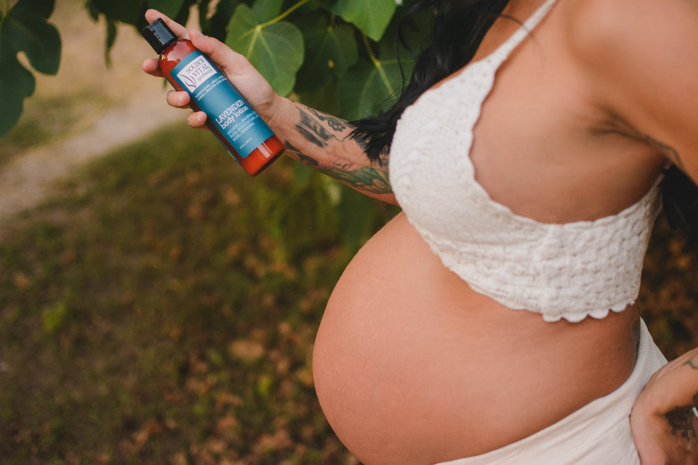 Pregnant woman in white bra holding lavender body lotion