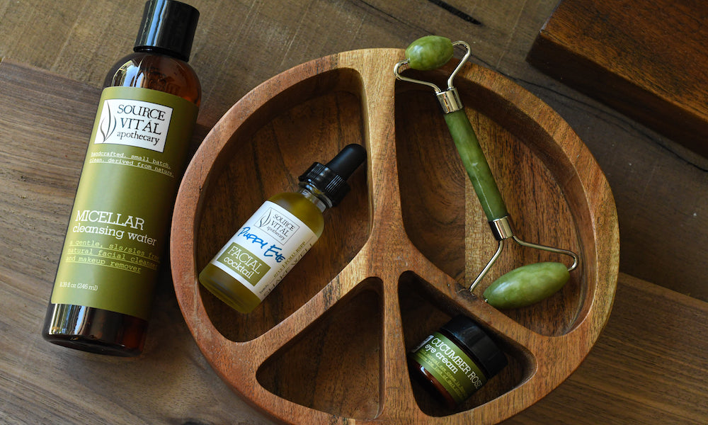 Source Vitál Puffy Eye Kit on wooden tray. Featuring Micellar Cleansing Water, Puffy Eye Cocktail, Cucumber Rose Eye Cream, and Jade facial roller.