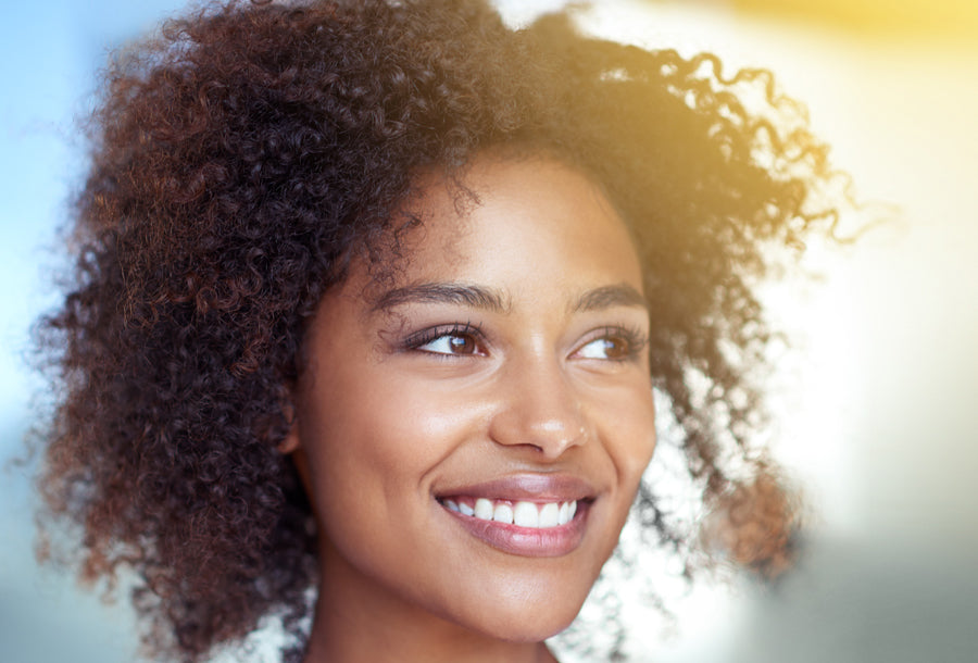 young black woman with curly hair smiling against blue and yellow background