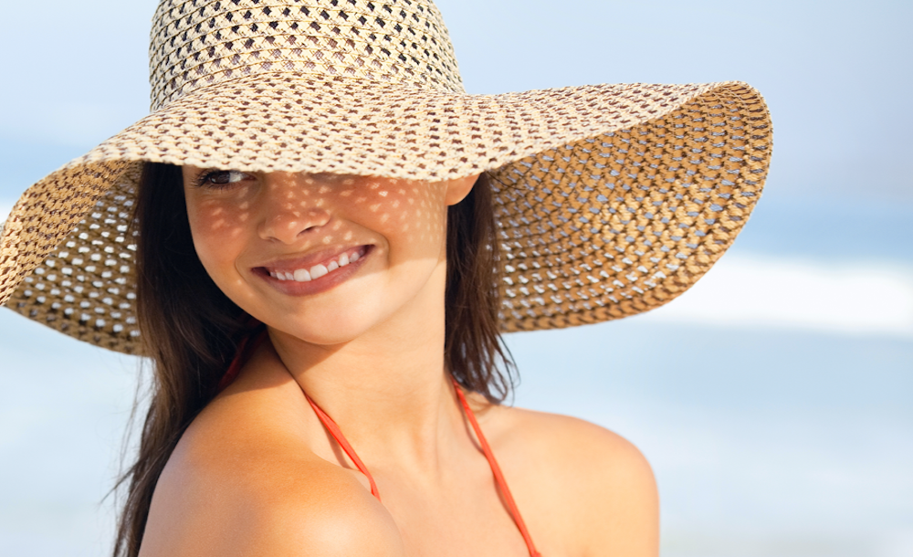 Woman wearing protective sun hat on a sunny summer beach
