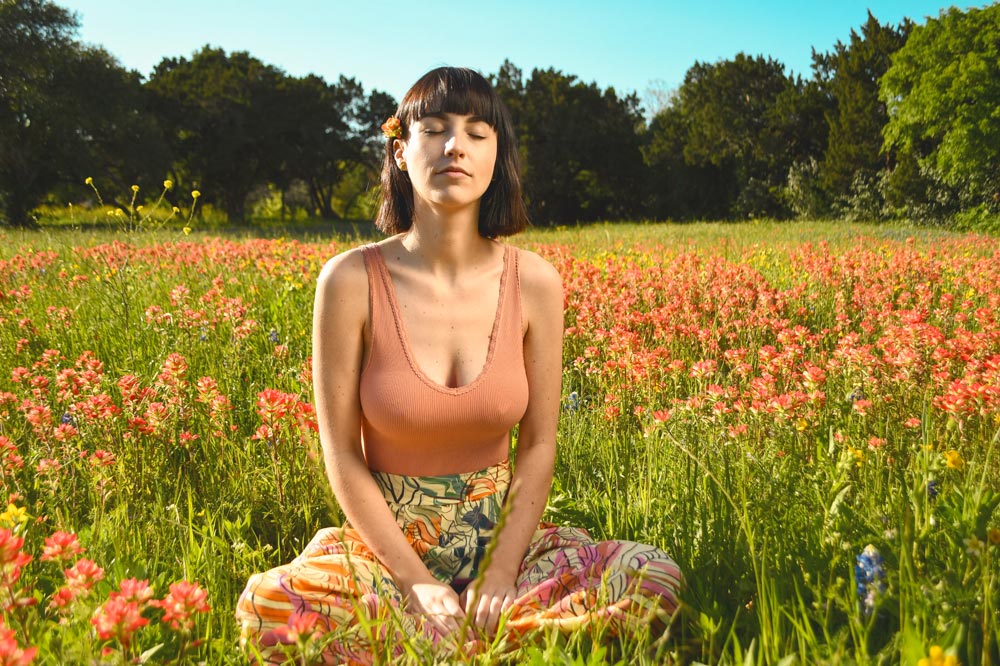 Woman meditating in field of wildflowers