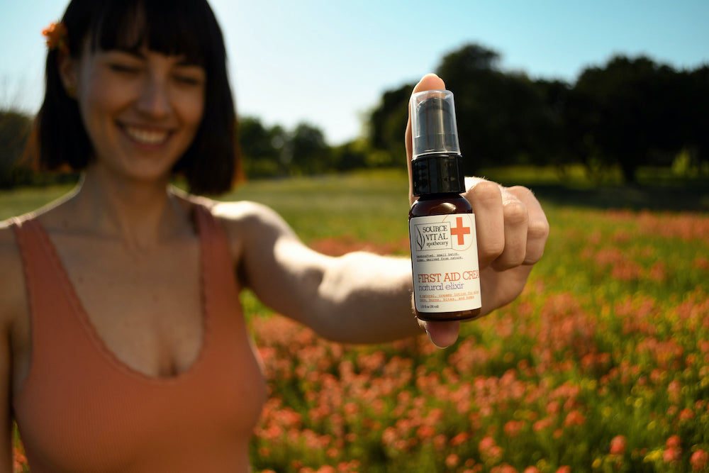 Woman holding first aid spray in a field of orange flowers