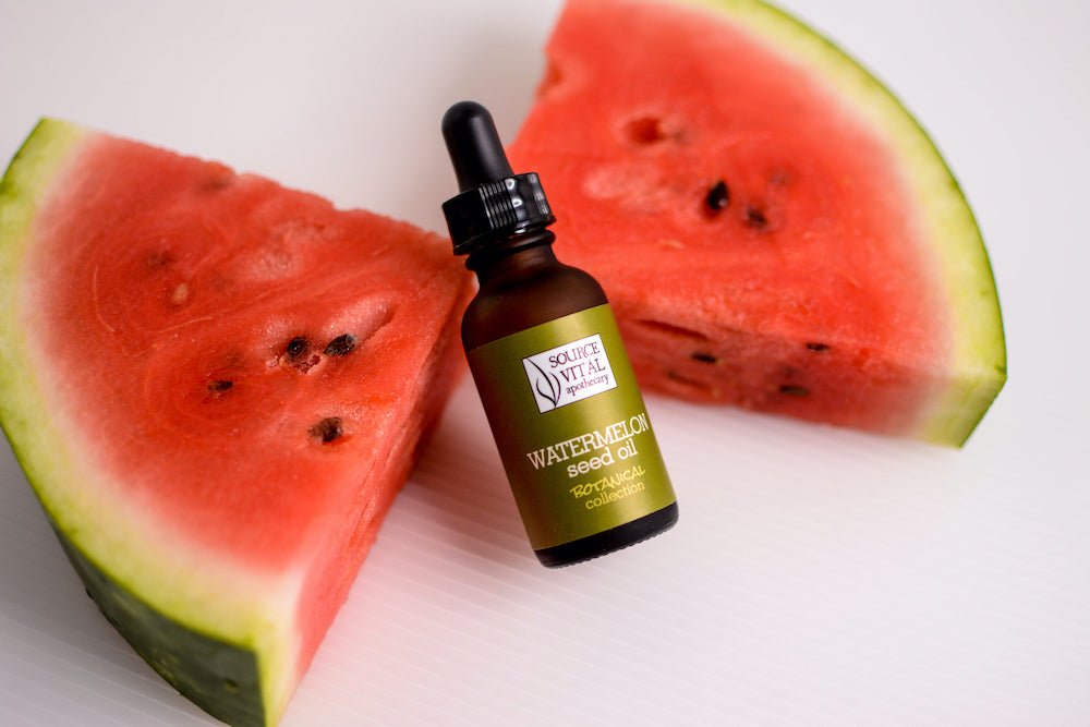 Source vital Apothecary Watermelon Seed Oil Bottle leaned up against two watermelon slices