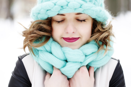 Girl outside in snow with blue hat and scarf